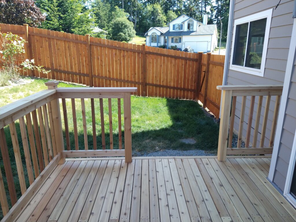 A Wooden Deck With A Fence And A Small Yard